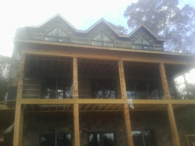 Dormers and porch framing on a large log home under construction — Roof Coating work by our crew in Everett