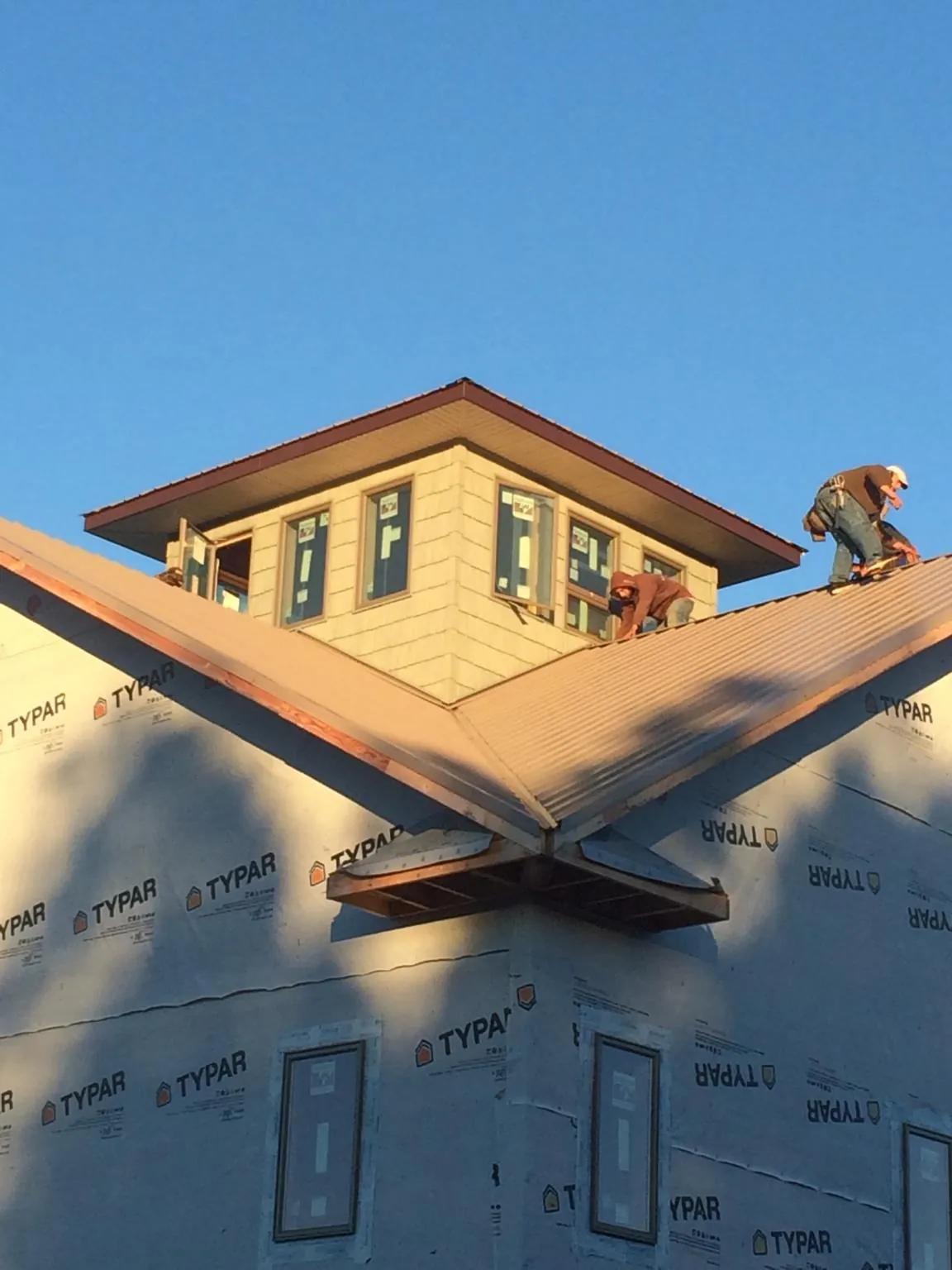 Roofers working around a rooftop cupola on a new metal roof at sunset — Roof Waterproofing in Everett by Roofing Brothers